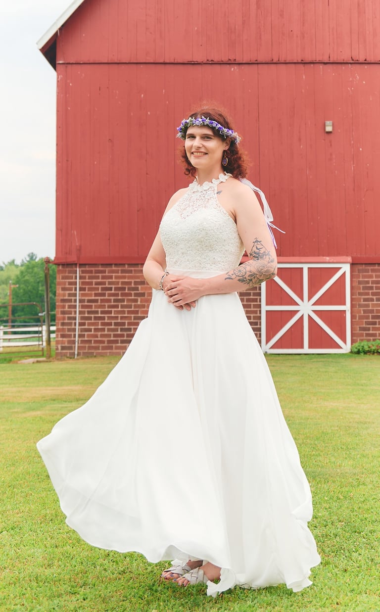 a woman in a white dress standing in front of a barn