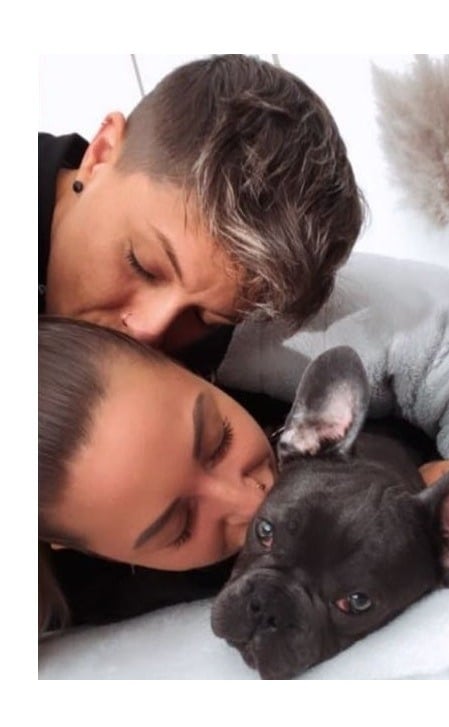 a man and woman cuddling up to a puppy