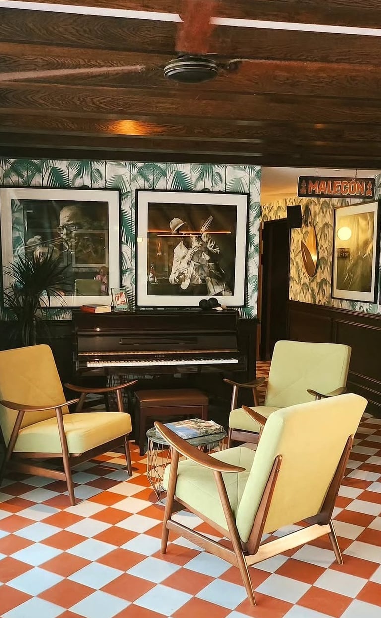 Mid-century modern jazz lounge featuring lime green armchairs, a piano, and tropical palm wallpaper.
