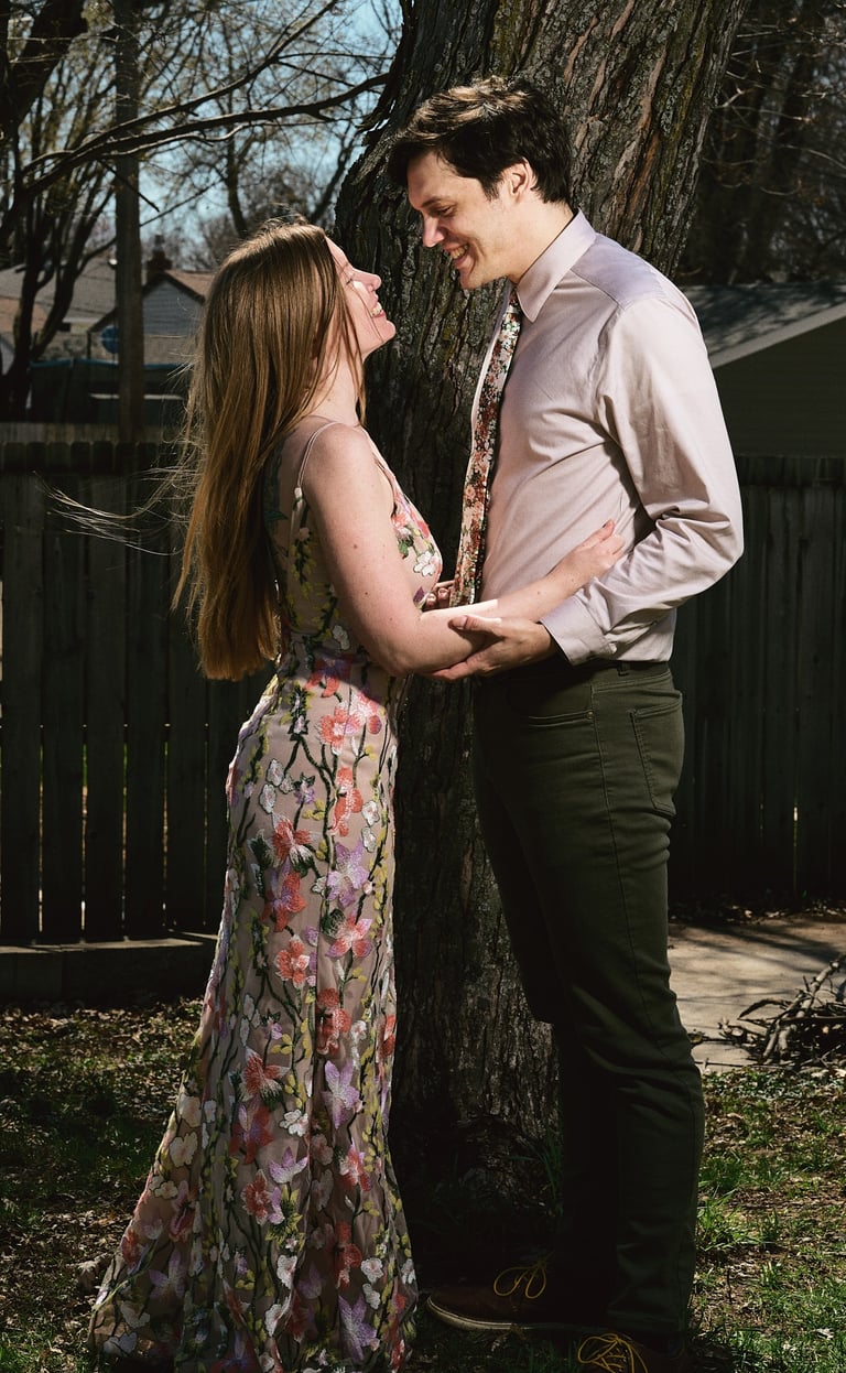 a man and woman facing each other and standing in front of a tree