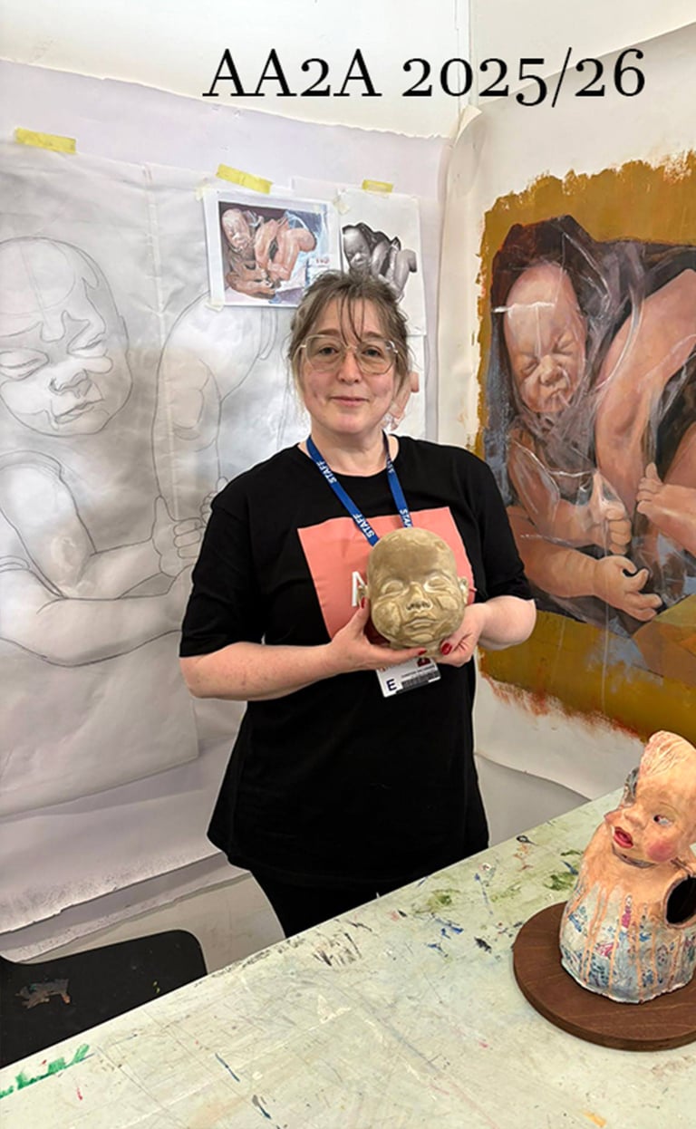 A studio photograph at the University of Chester of the artist, Christine Gallagher holding her clay head sculpture