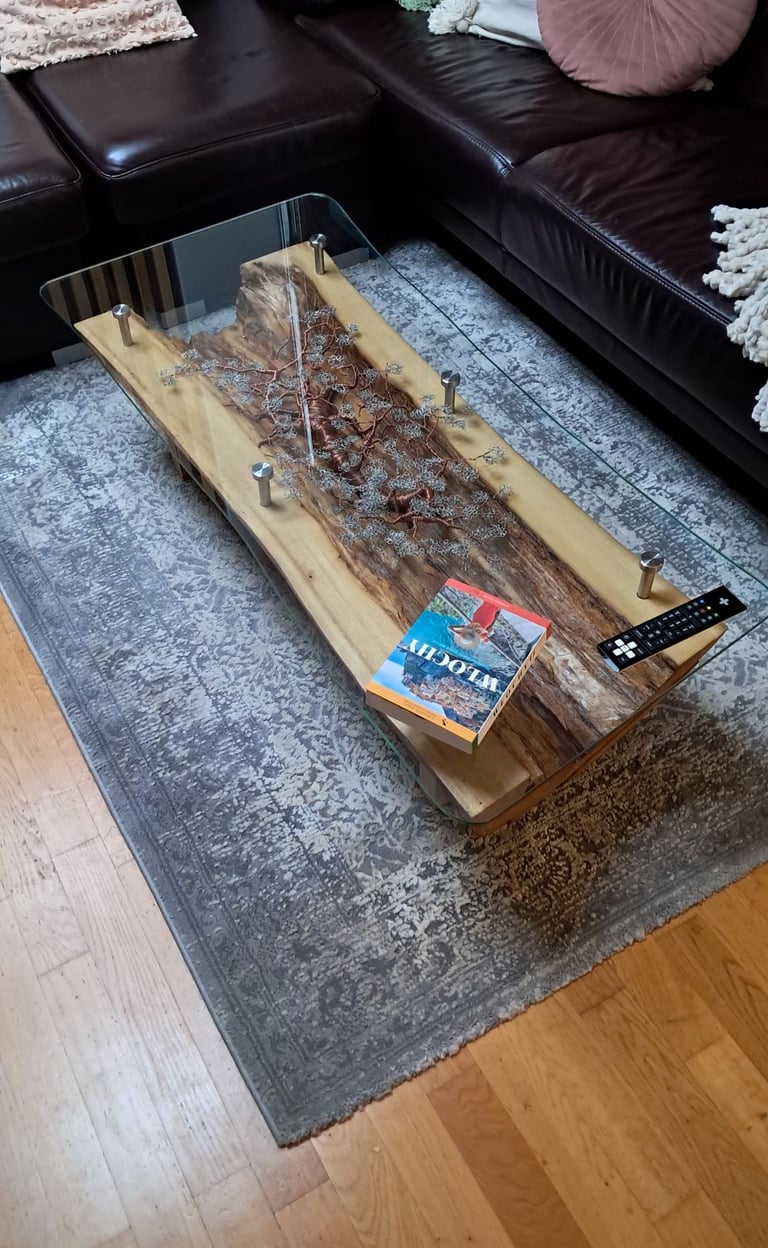 a coffee table with a glass top and a wooden table with a tv remote control