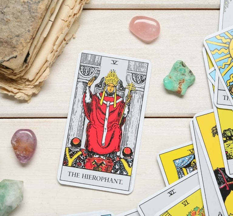The Hierophant tarot card on a stack with crystals for tarot study and learning.