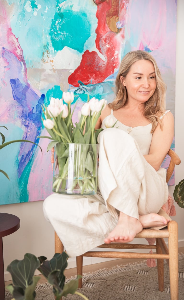the therapist Saija Uussaari sitting in a chair with a vase of flowers