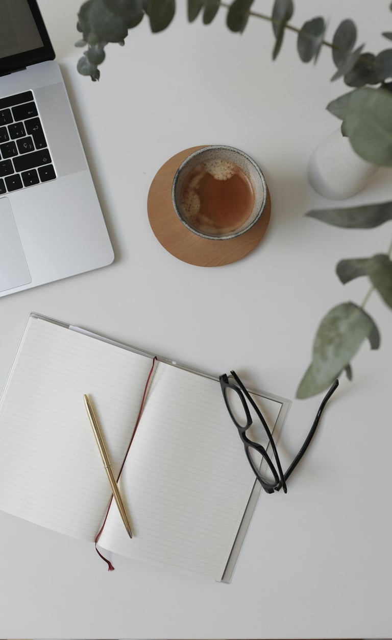 Workspace of a business operations support specialist with a laptop, coffee, and notebook