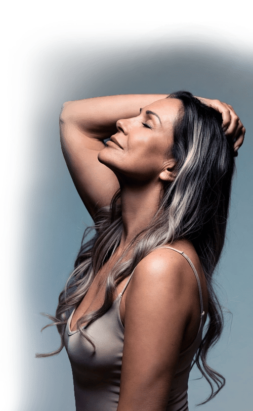 A middle-aged woman with long wavy hair and closed eyes posing for a portrait against a blue background.