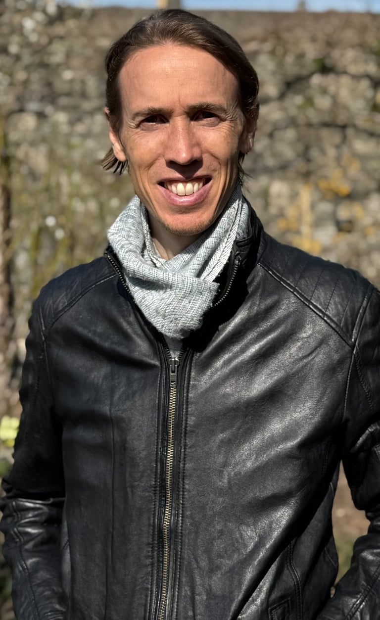 Photo of Chris, Wellbeing and health coach South Wales, standing outside in the sun wearing leather jacket