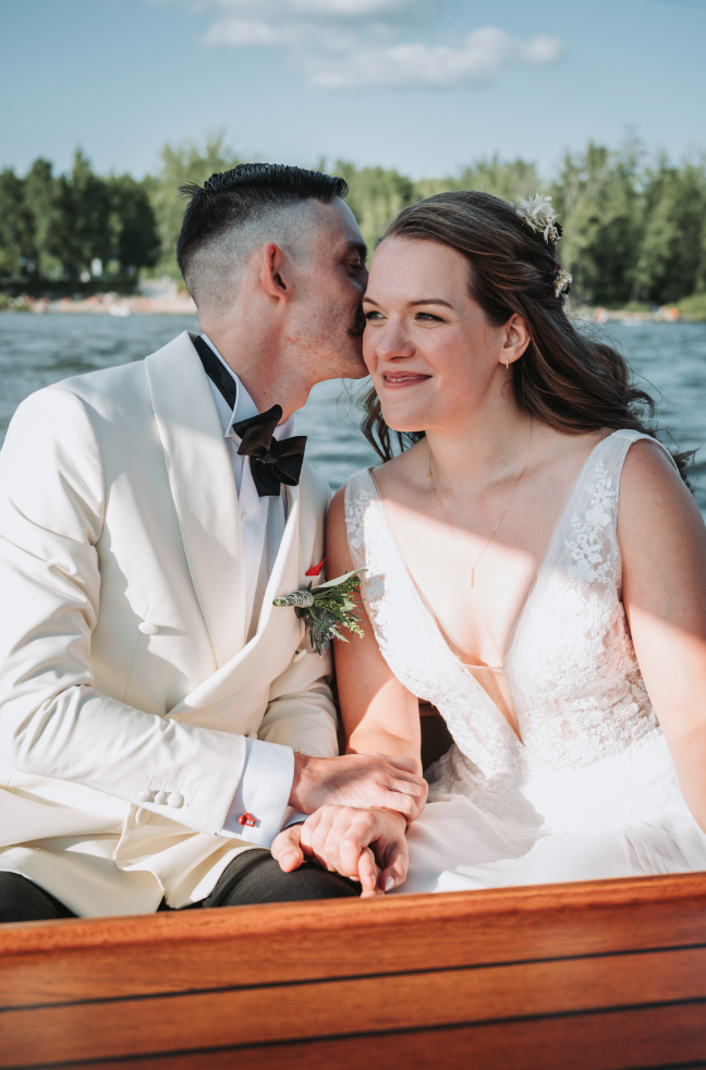 Une mariée et un marié partageant un moment romantique sur un bateau lors de leur mariage d’été.