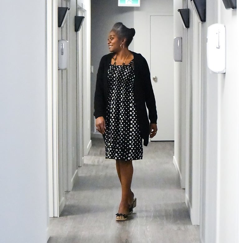 Confident Dr Bisi Aluko walking through modern medical clinic