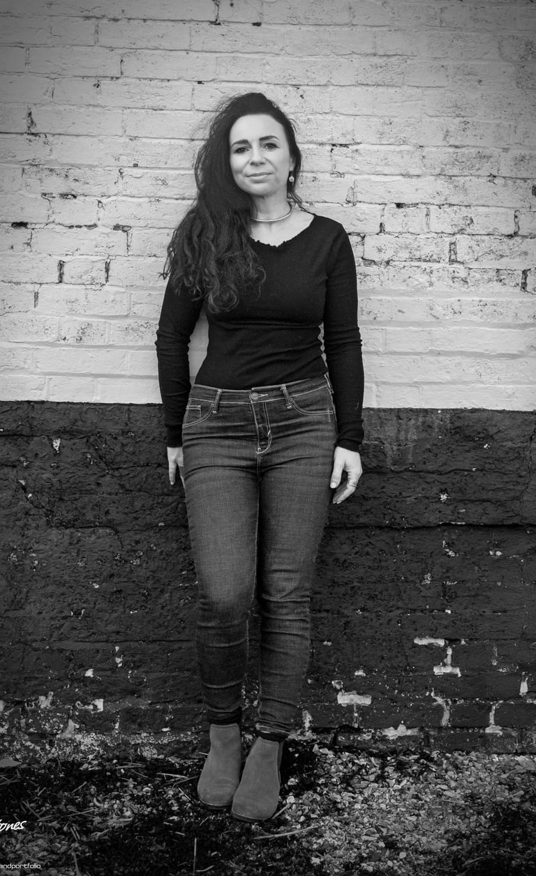 Black and white portrait of Helen Spooner, pianist and vocalist, standing against a brick wall.