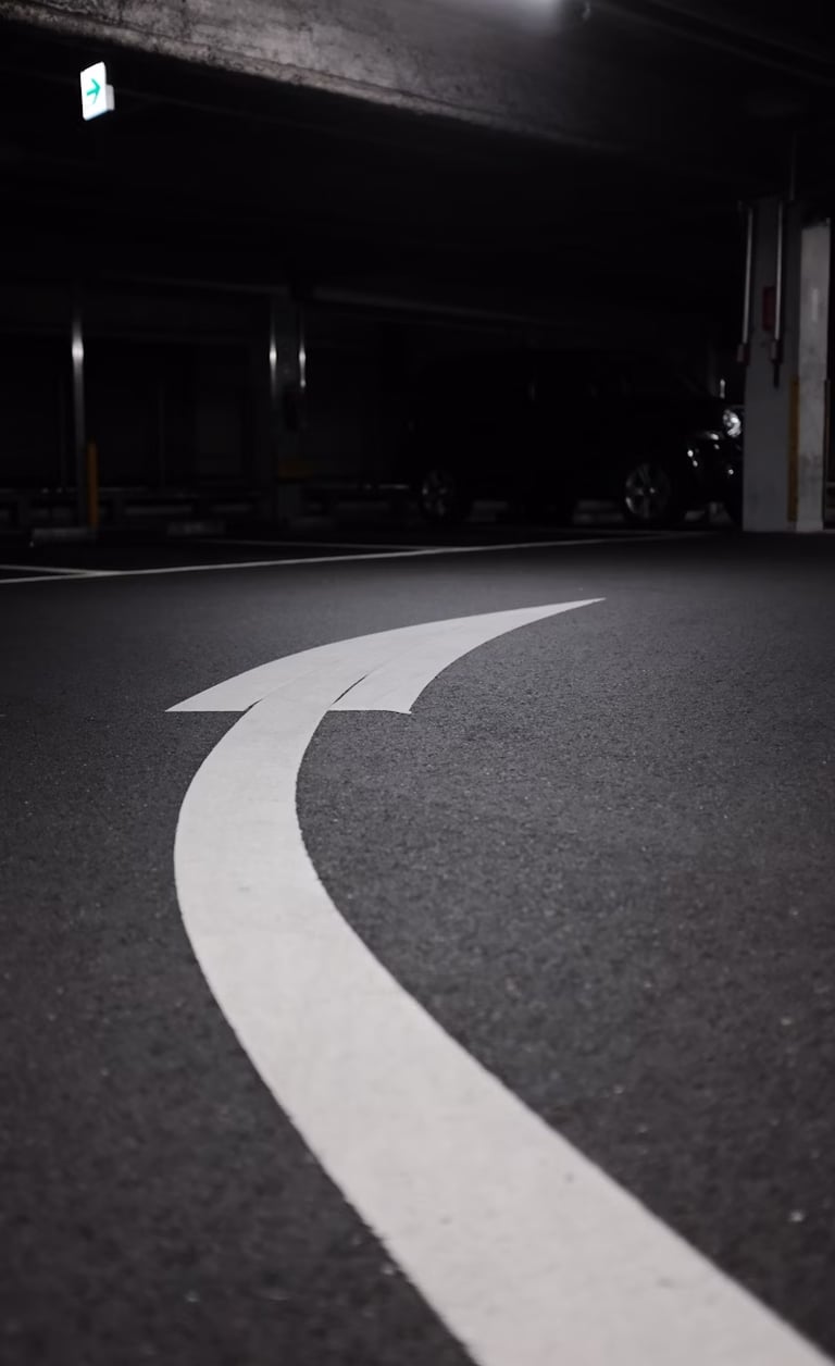 Una figura de una flecha curveada hacia la derecha y pintada sobre el pavimento.