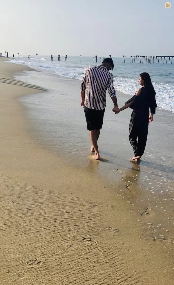 Couple walking along Alleppey Beach with the historic old pier in the background, enjoying a seaside evening in Kerala