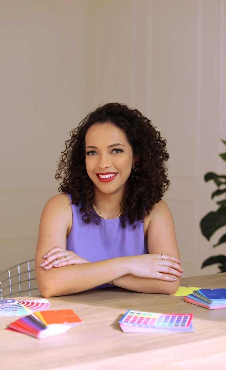 Mulher cacheada sorridente com braços cruzados, oferecendo serviços de coloração pessoal