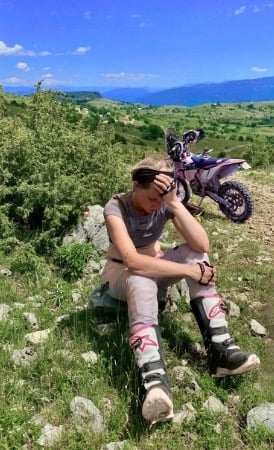 Yogalehrerin-Anja-sitzt-erschöpft-neben-dem-Enduromotorrad