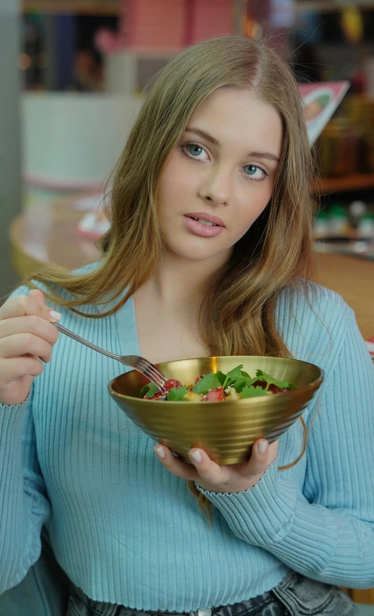 a woman in a blue sweater holding a bowl of salad