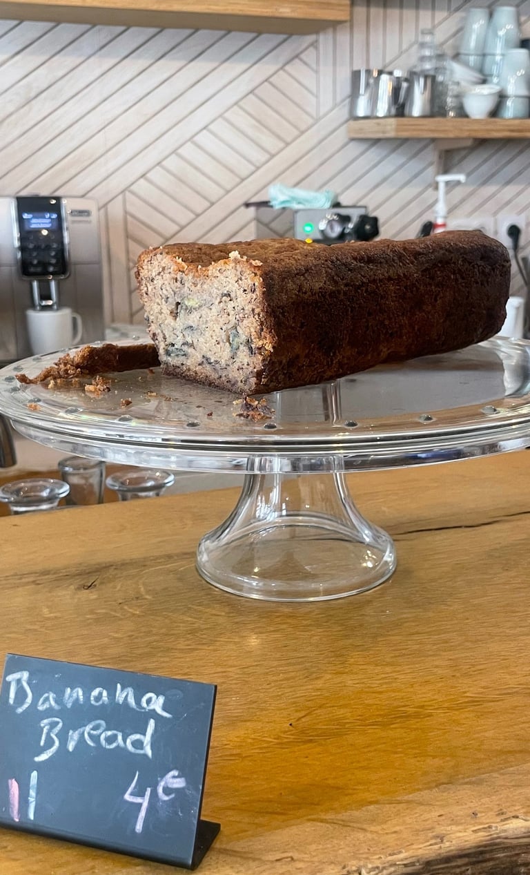 A slice of homemade banana bread on a glass display stand
