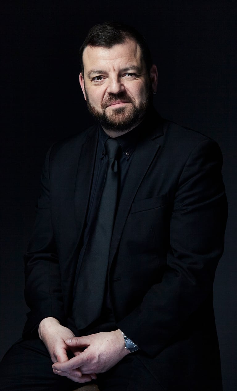 Professional portrait of Steven Devine, harpsichordist and conductor.  Black suit, shirt and tie