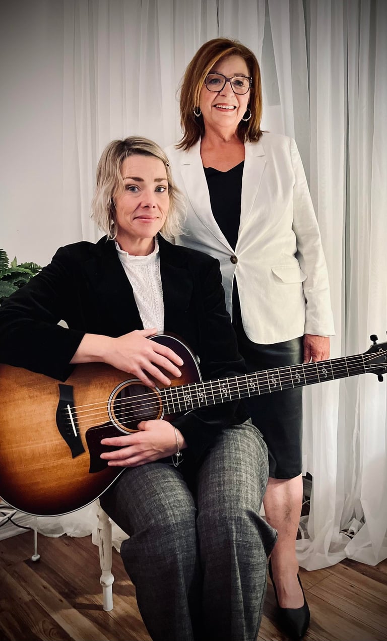 Colette et Caroline Lupien posent, l’une assise avec une guitare, l’autre debout, souriante. 