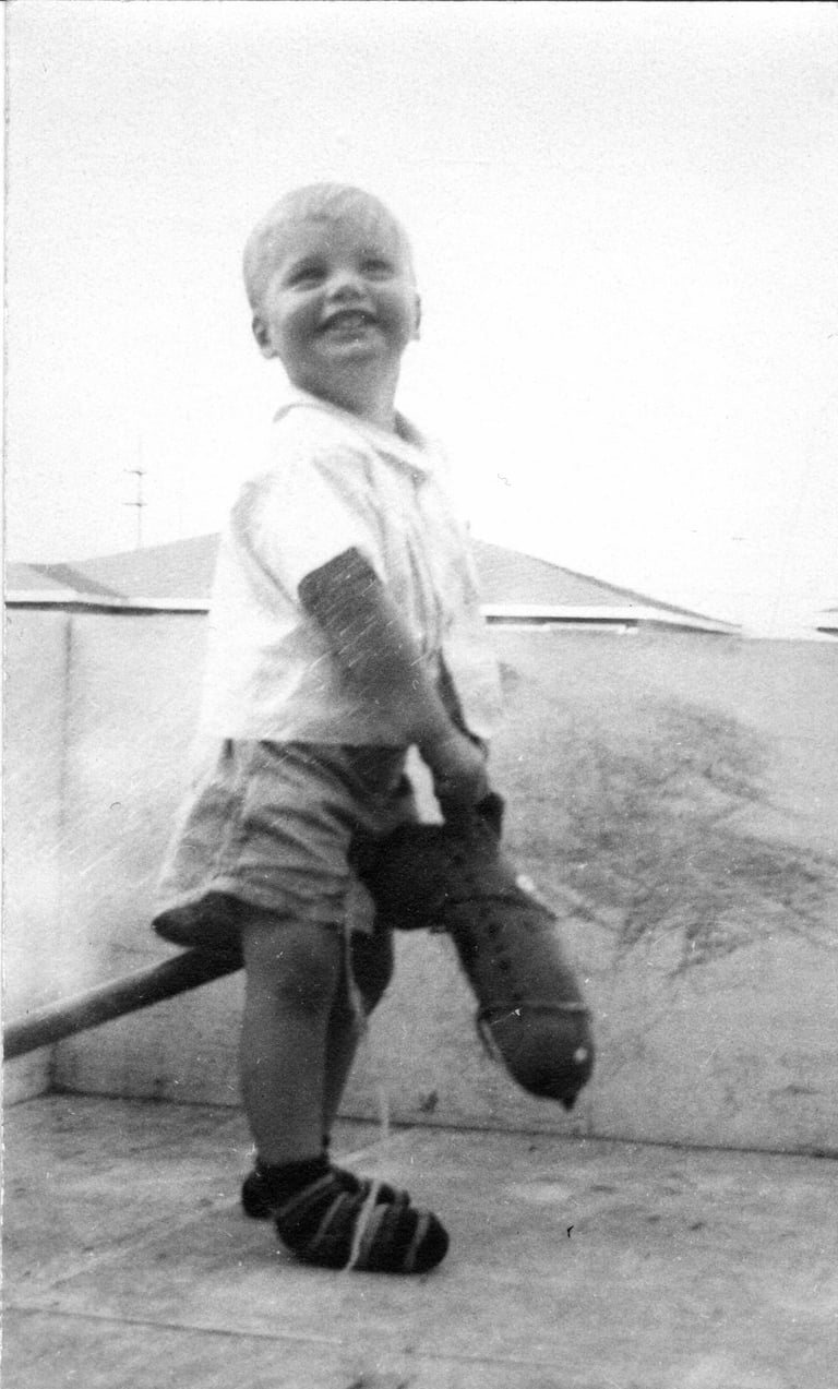 Childhood black & white photo of Cam Beard. founder of Carrots by Cam, riding a hobby horse