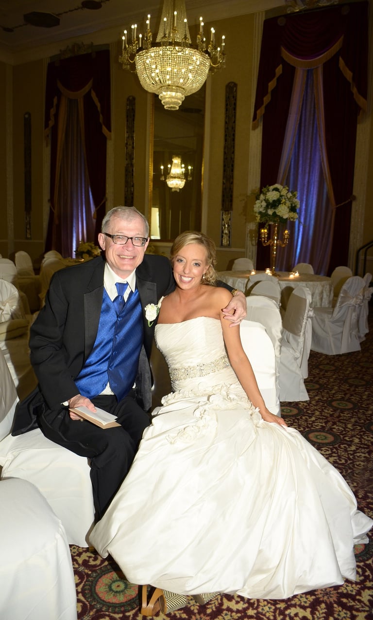 a bride and father-in-law sitting next to each other on in a ball room