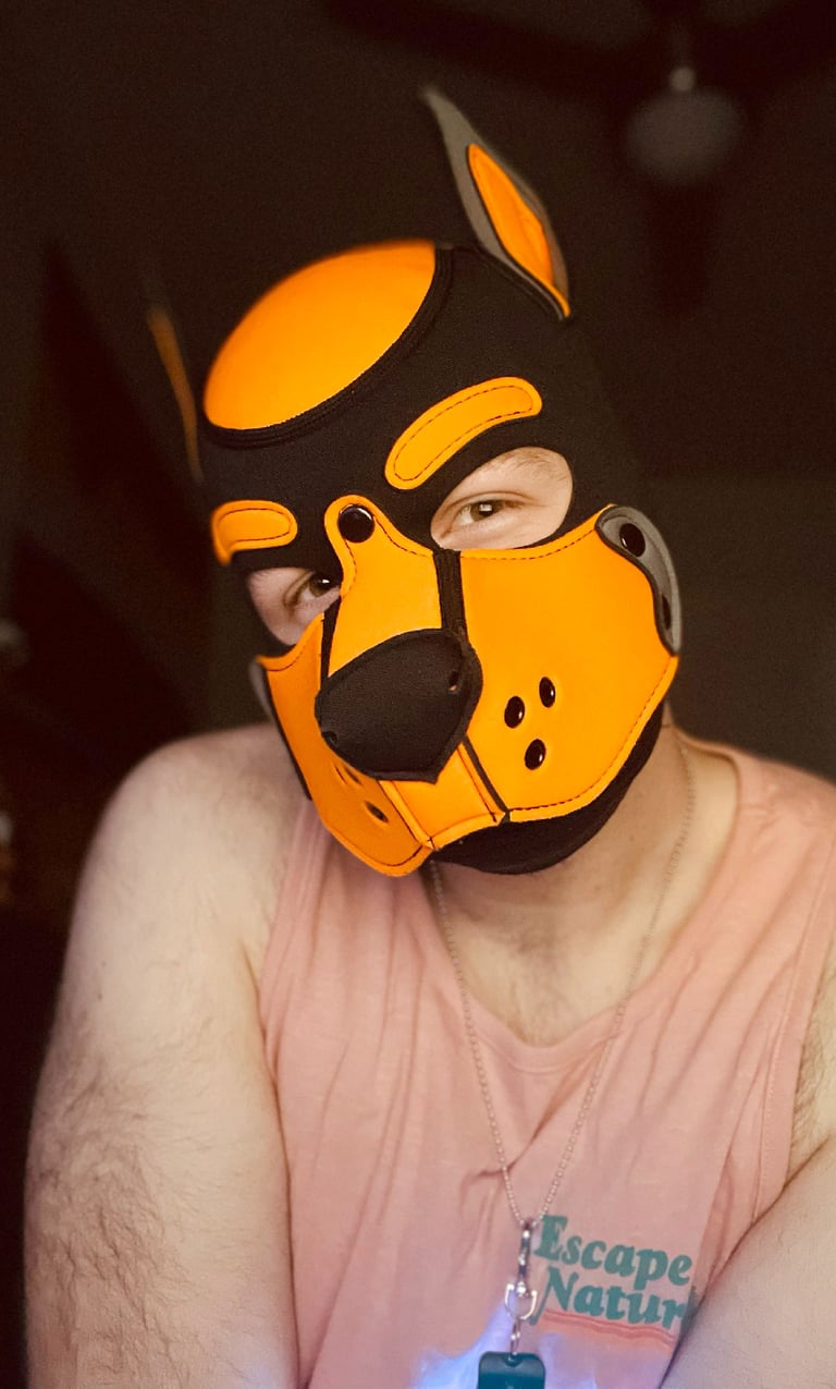 Man. posing wearing a pup mask.