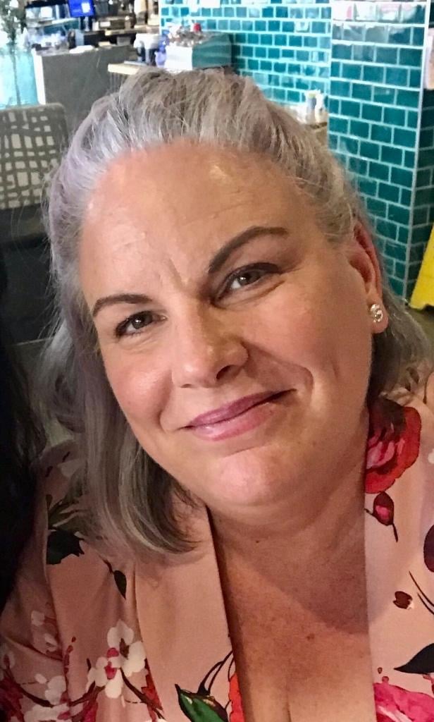 a woman with grey hair and a pink shirt