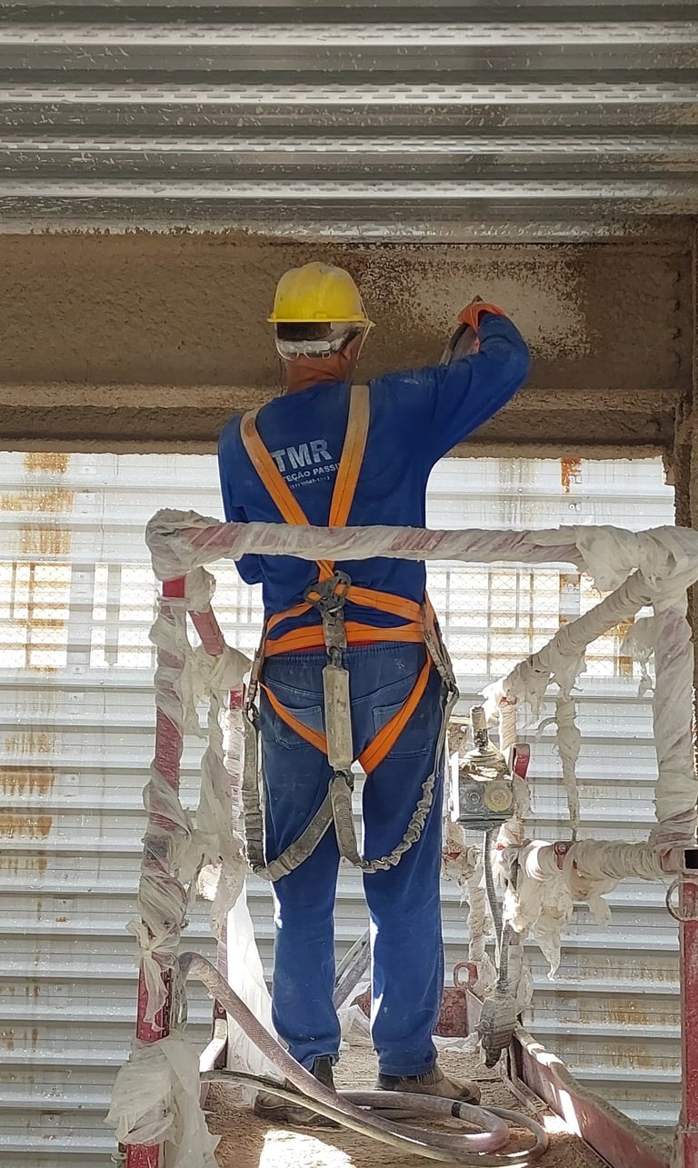 Homem Aplicando Argamassa Contra Fogo em Estrutura Metálica