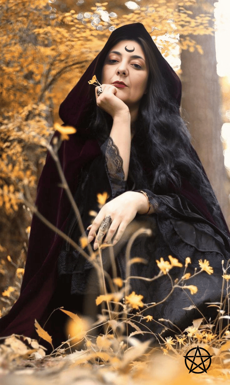 a mystical woman with a crescent tattooed on her forehead wearing a black dress and a black cape sit