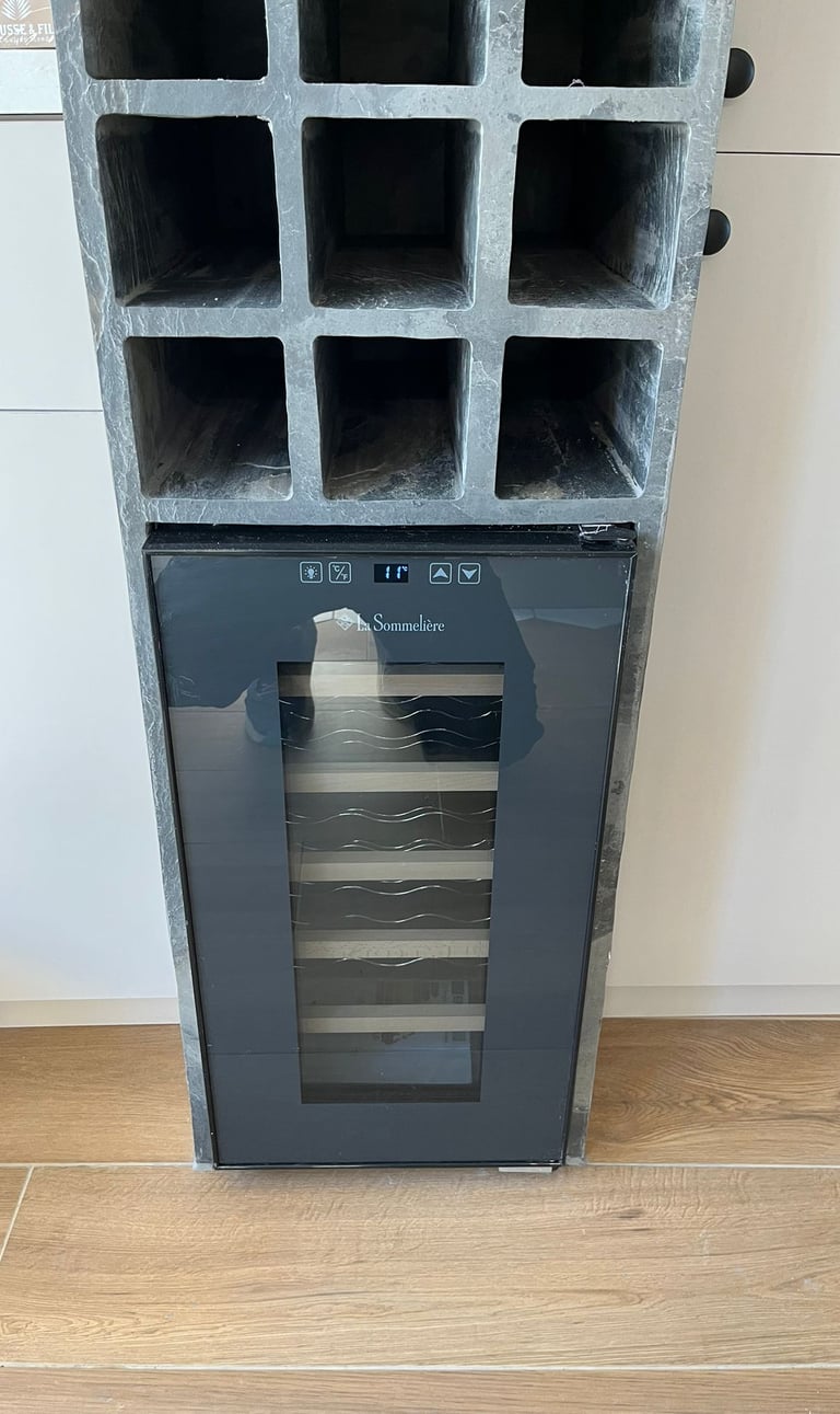 A La Sommeliere wine cooler fridge built into a gray concrete storage rack in a modern kitchen.