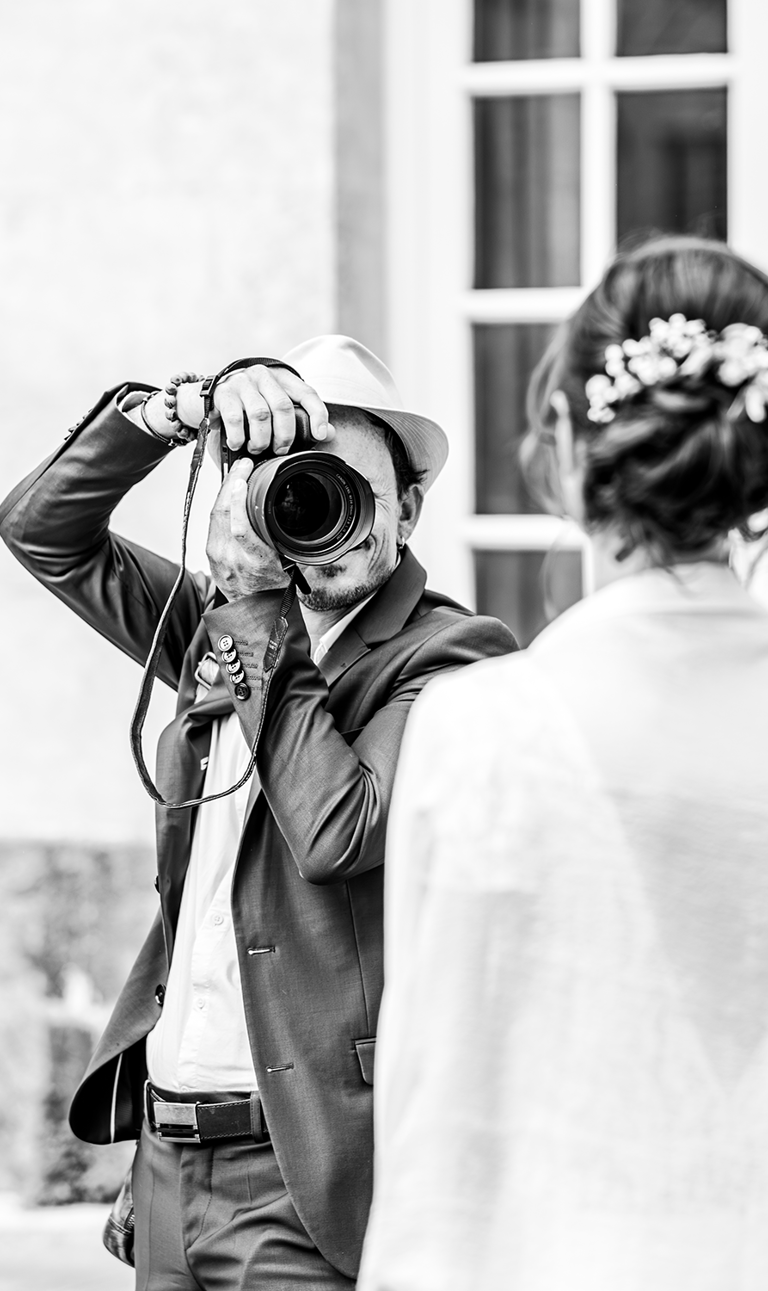 photo en noir et blanc de Dimitri Desrues en costume avec son appareil photo