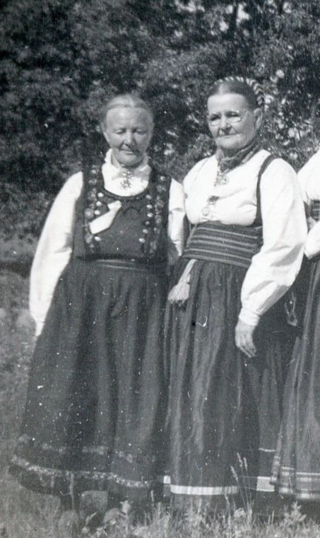 a black and white image of two women in bunad