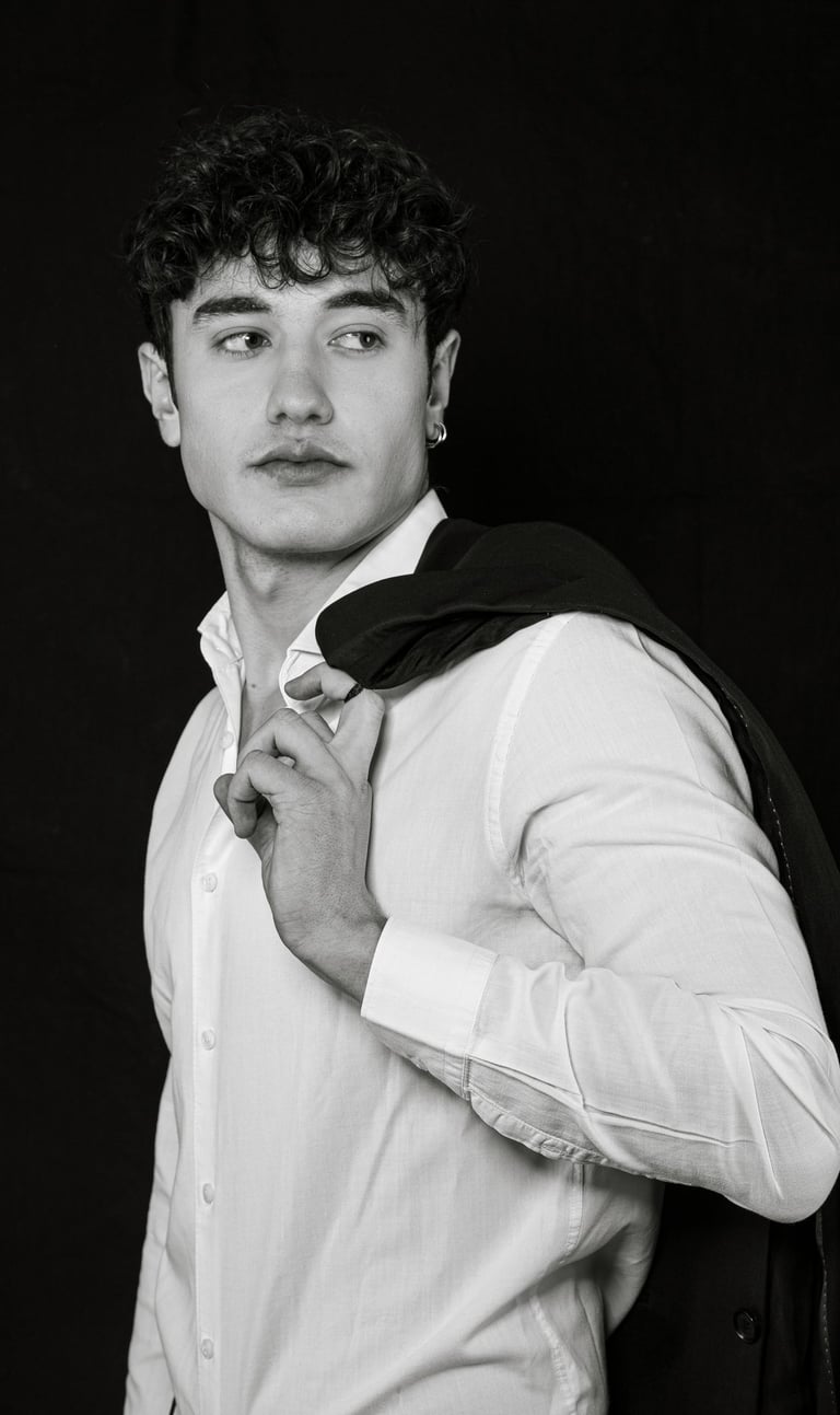 Man in smart casual wear taking a half-body selfie while looking away from camera in natural light