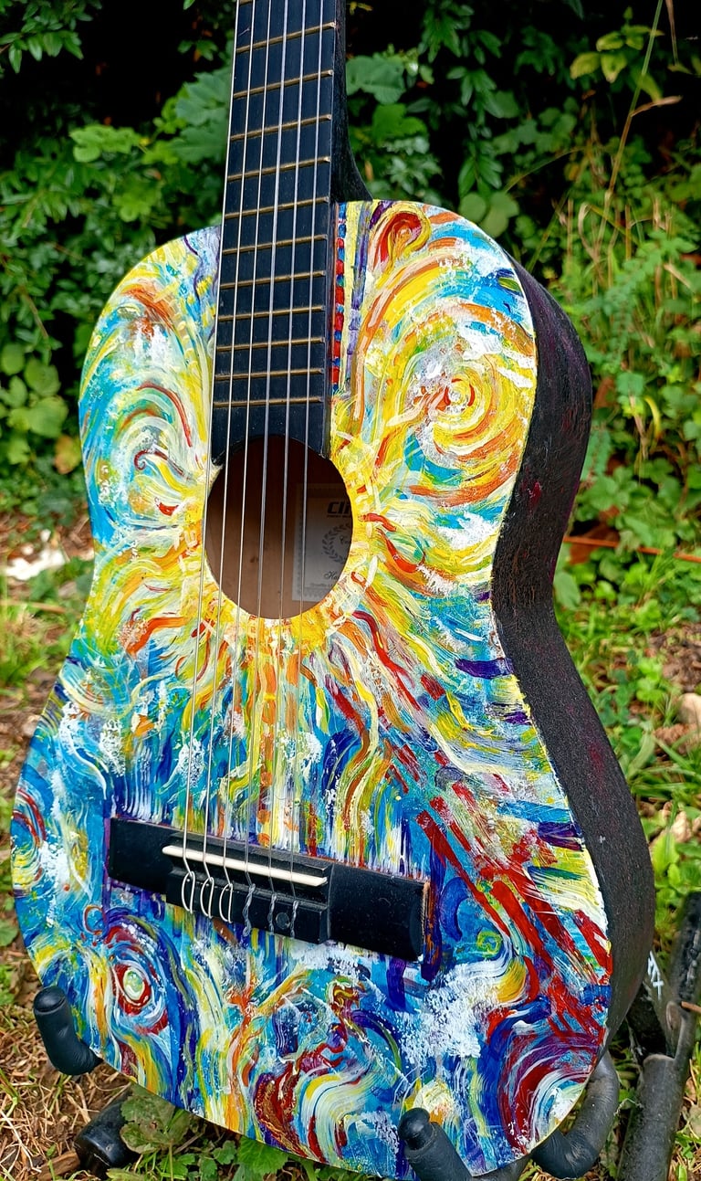 peinture sur guitare aux couleurs vives, avec un soleil autour de la rosace et des formes abstraites