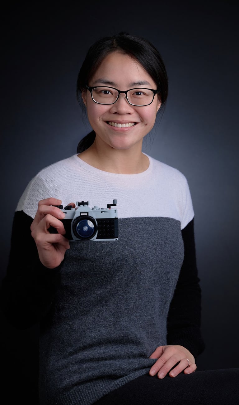 a woman in glasses and a sweater holding a lego camera