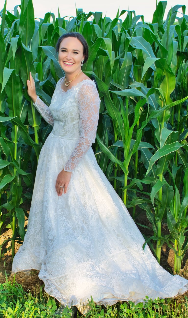 a woman in a white dress standing in front of a corn field