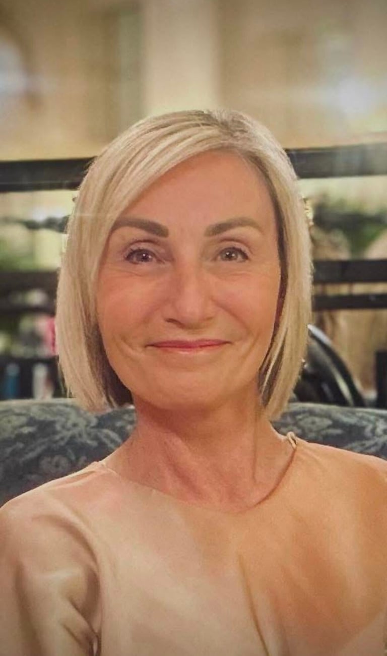 Lisa, smiling, with a blonde bob hairstyle wearing a peach-colored silk blouse.