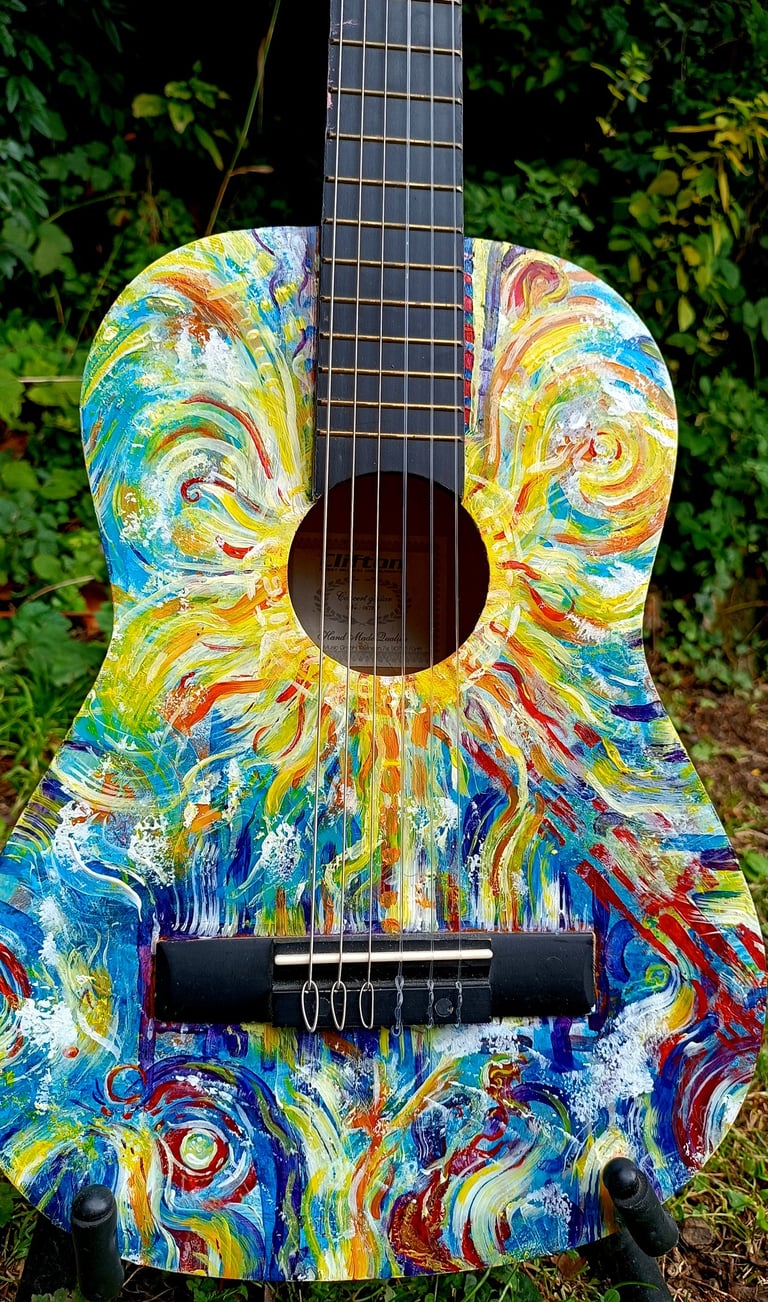 peinture sur guitare aux couleurs vives, avec un soleil autour de la rosace et des formes abstraites