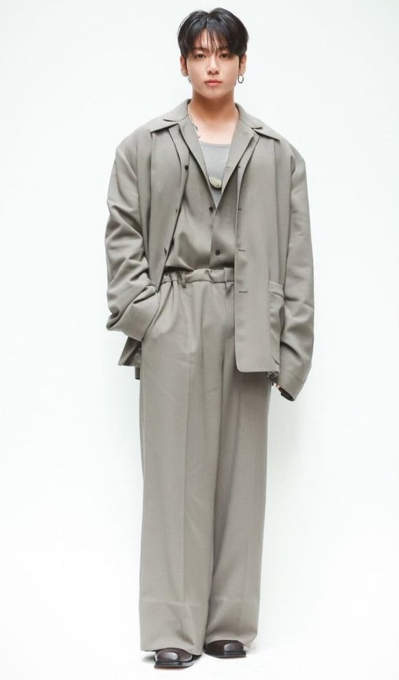 Jungkook at NYFW wearing an oversized grey suit at the Calvin Klein show.