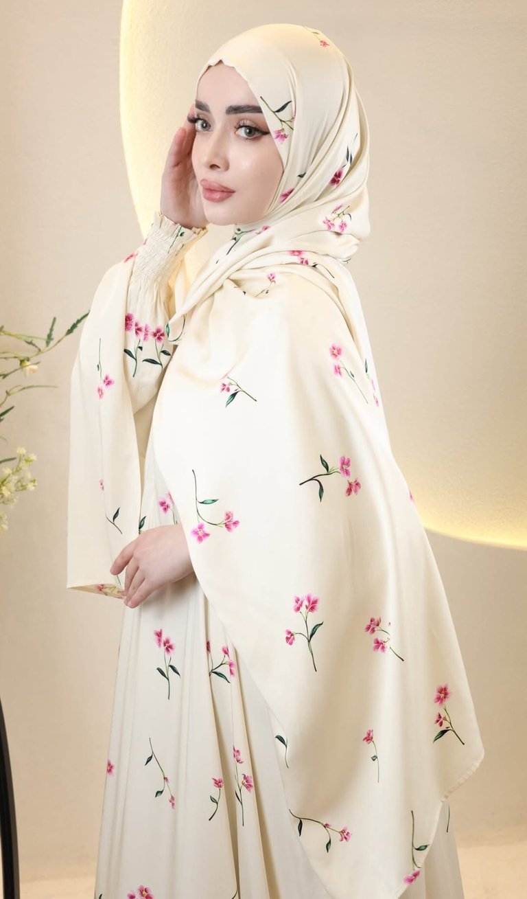 Elegant woman wearing a cream-colored floral hijab and matching abaya with pink flower prints.