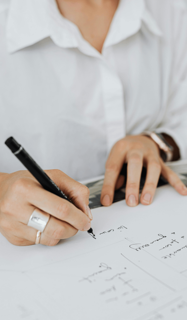Zbliżenie na ręce kobiety podpisującej dokument długopisem, ubrana w białą koszulę