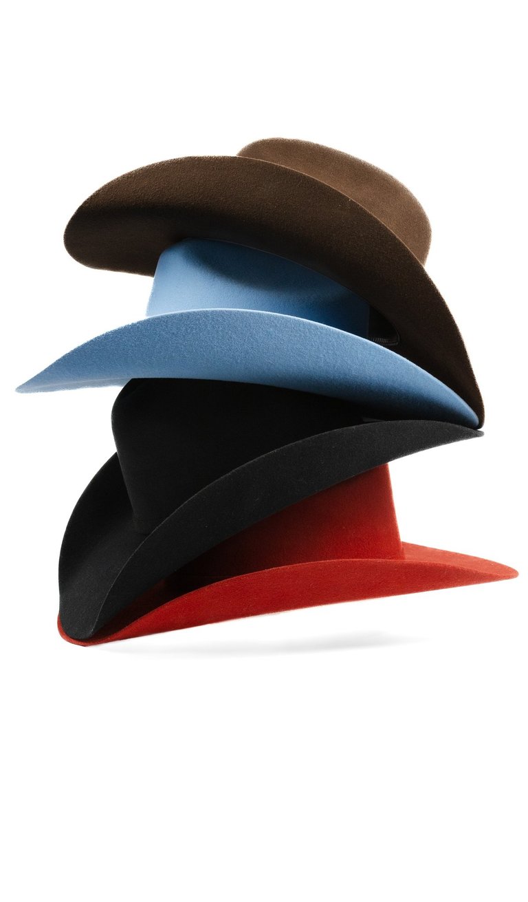 A stack of colorful wide-brimmed felt fedora hats in brown, light blue, black, and red.