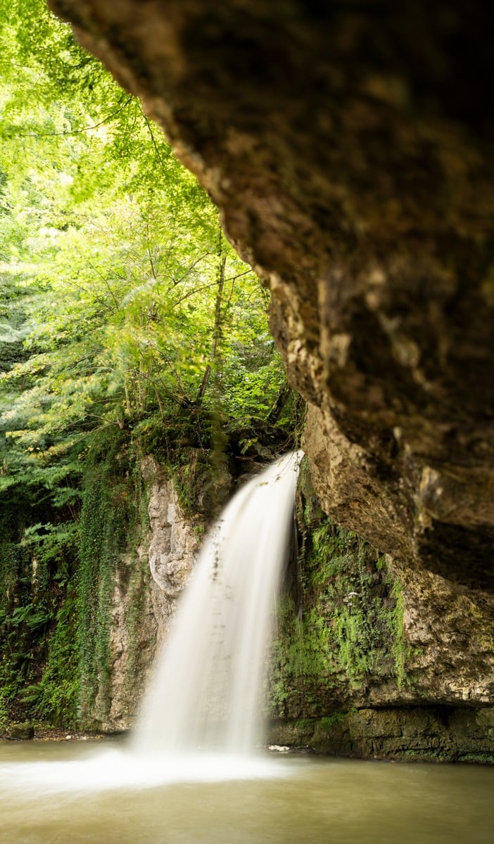 a waterfall in a cave in the woods