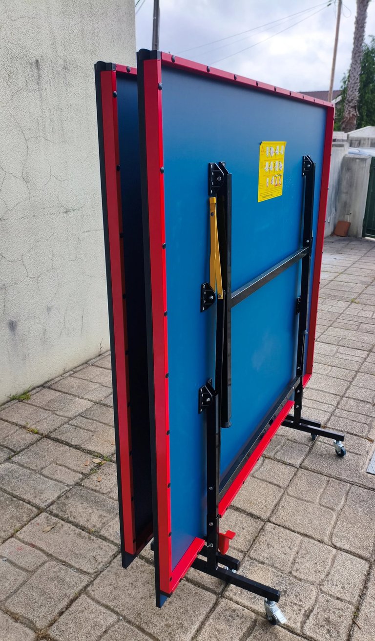 Mesa de ténis TOPGIM Training dobrada e em posição de arrumação com rodas