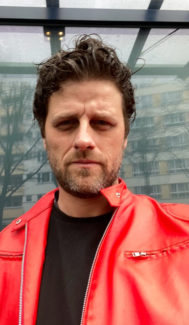 Rob Phillimore PR Consultant in Berlin, Germany wearing a red jacket and black t-shirt