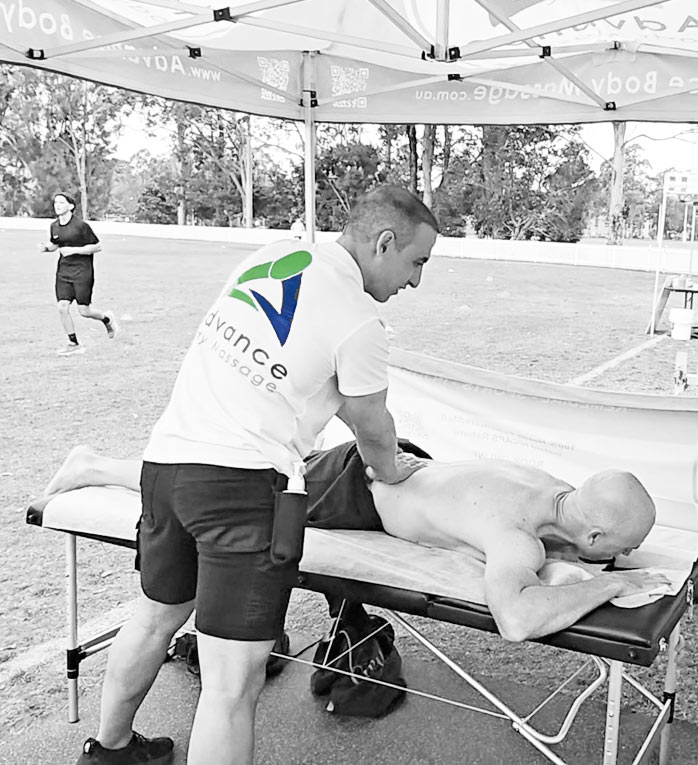 Male massage therapist performing remedial massage on a males back