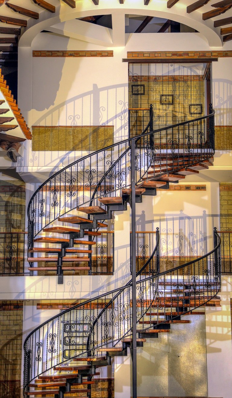 Elegant wrought iron spiral staircase with wooden steps inside a modern rustic home.