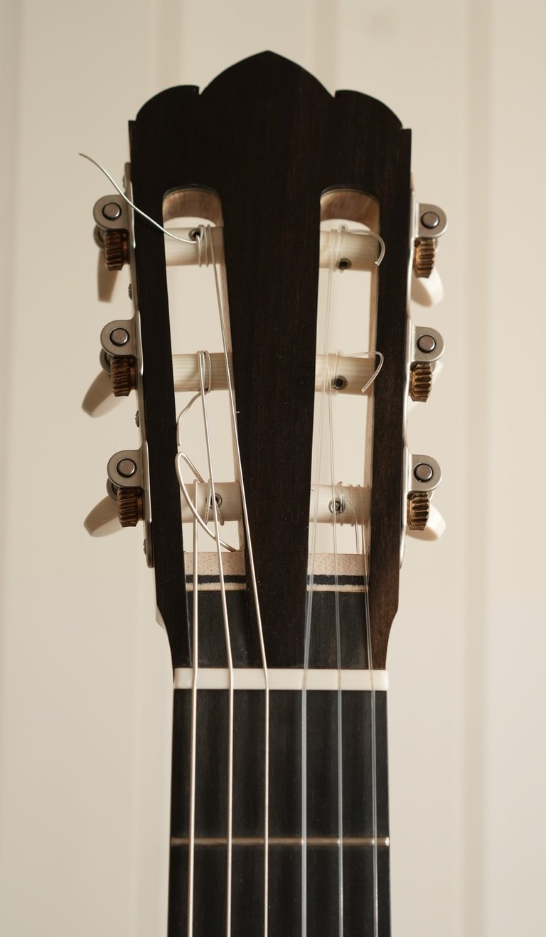 Close-up of a classical guitar headstock with nylon strings and tuning pegs.