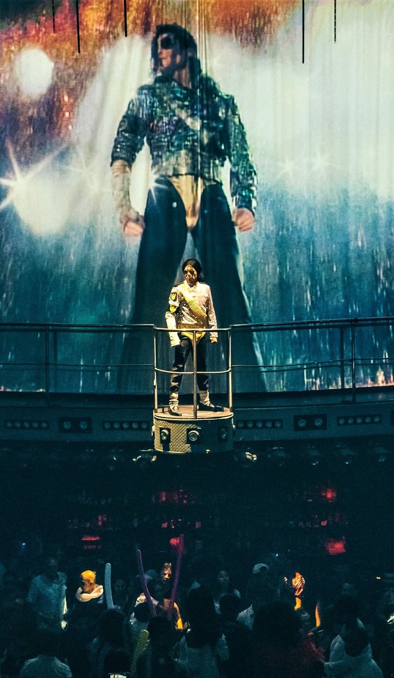 a man standing on a stage with a giant painting of a man on a stage cocobongo punta cana