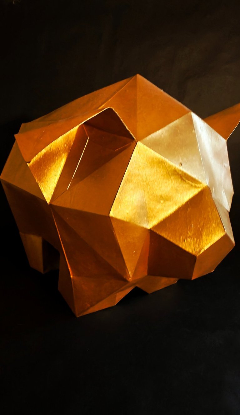 Low poly geometric gold pig sculpture on a black background for wall art or office decor.