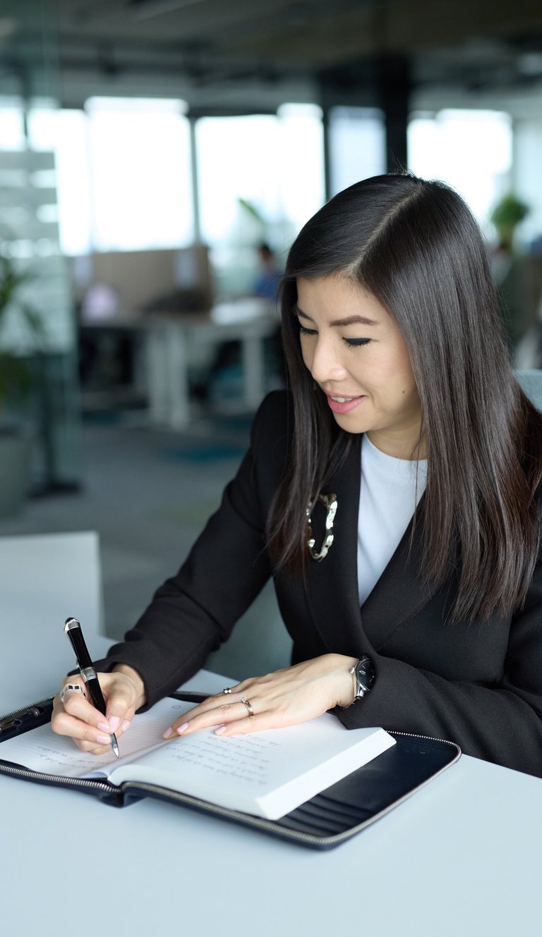 a woman in a suit is writing on a notebook